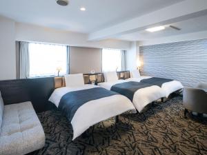 a row of beds in a room with a couch at APA Hotel Tokyo Ojima in Tokyo