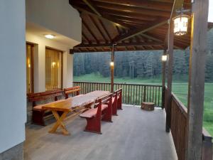 a porch with a wooden table and benches on a deck at Daisy Forest in Borino