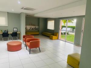 a waiting room with orange and yellow chairs and tables at Play Ilhotas - Centro Teresina in Teresina