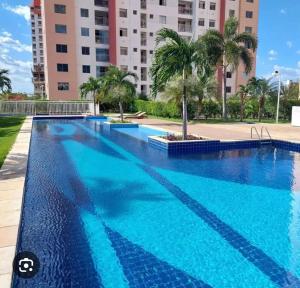 a large blue swimming pool with palm trees and buildings at Play Ilhotas - Centro Teresina in Teresina