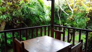 a wooden table with a glass on a balcony at Kubu shanti 1 in Ubud