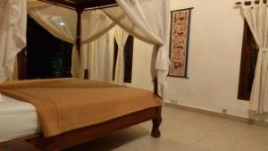 a bedroom with a canopy bed and a window at Kubu shanti 1 in Ubud