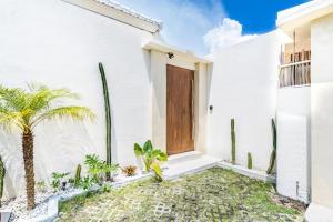 a white house with a door and a palm tree at Villa Wedas in Canggu