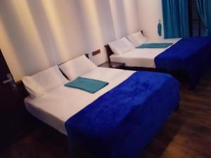 two beds with blue sheets in a room at Ella Field Side View Rooms & Cafe in Demodera