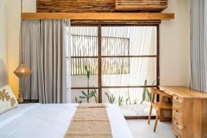 a bedroom with a bed and a desk and a window at Villa Wedas in Canggu +34 photos