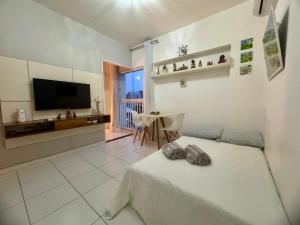 a bedroom with a bed and a television and a table at Encantos no Porto da Barra in Salvador
