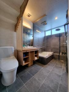 a bathroom with a toilet and a sink and a tub at Yama Sakura in Furano