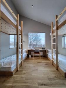 a room with three bunk beds and a desk at Yama Sakura in Furano +8 photos