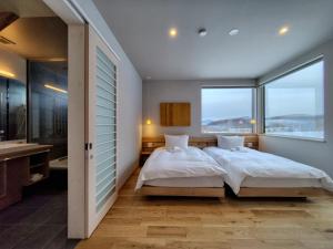 a bedroom with two beds and a large window at Yama Sakura in Furano