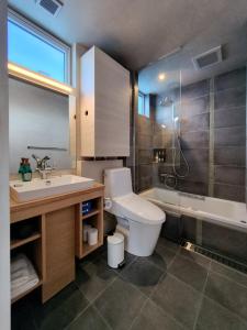 a bathroom with a toilet and a sink and a tub at Yama Sakura in Furano