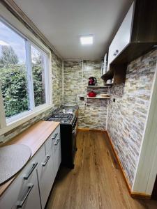 a kitchen with a stove and a brick wall at Departamentos Sol del Sur in Quellón