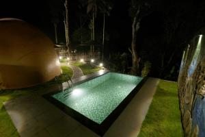 a swimming pool in a yard at night at Lake Lagoon Moonhills in Mennānyam