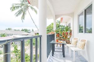 a porch with a table and chairs and a palm tree at Bijunas Homestay in General Luna