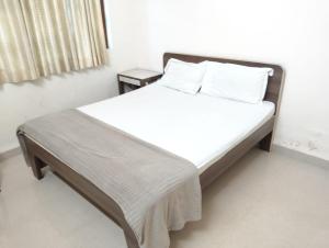 a bed with white sheets and pillows in a room at Rich nest apartments colva in Colva