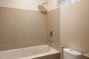 a bathroom with a bath tub and a toilet at GGuesthouse in Kuta Lombok
