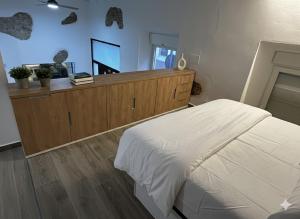a bedroom with a white bed and a wooden dresser at Villa Abril en el Porvenir in Seville
