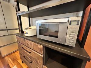a microwave on a counter in a kitchen at ORENCHii bed7台広々1棟貸 in Yomitan