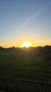 a field with the sun setting in the horizon at The Cozy Nook - Dorm in Batangas City