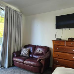 a living room with a brown leather couch and a dresser at Seventy-Four on Ramsay in Taupo