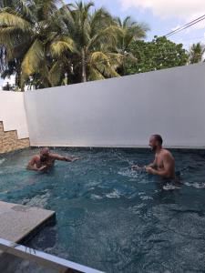 two men playing in a swimming pool at Ceylon Lodge - Airport Transit Hostel in Negombo +87 photos