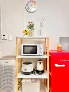 a microwave on a shelf next to a red refrigerator at Finetree House in Samgong +6 photos
