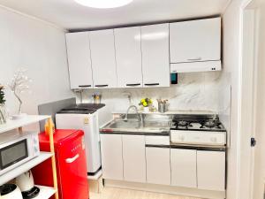 a kitchen with white cabinets and a sink and a stove at Finetree House in Samgong