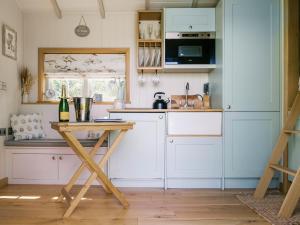 a kitchen with white cabinets and a wooden table at Herbie's Shepherd Hut - Uk50229 in Nottingham