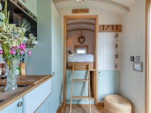 a small bedroom with a bed and a stool in a room at Herbie's Shepherd Hut - Uk50229 in Nottingham