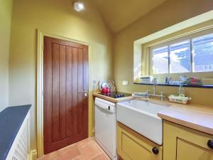 a kitchen with a sink and a wooden door at Oaklands Farm - Cottage 5 in Broughton