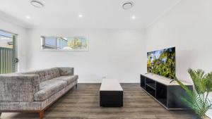 a living room with a couch and a flat screen tv at Little Gem in Northwest! in Riverstone