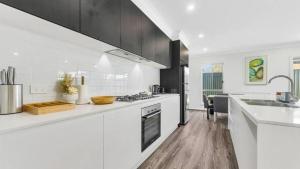 a white kitchen with a sink and a stove at Little Gem in Northwest! in Riverstone +9 photos
