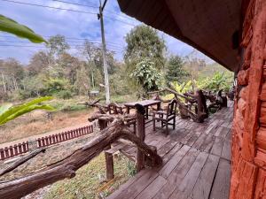 a wooden deck with a table and chairs on it at บ้านชนเผ่าแคมปิ้งแอนด์รีสอร์ท in Pang Mapha