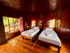two beds in a room with wooden floors and windows at บ้านชนเผ่าแคมปิ้งแอนด์รีสอร์ท in Pang Mapha +21 photos