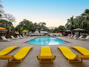 a swimming pool with yellow chairs and a group oficans at SoCo Chic Apartment Suites Close to Downtown in Austin