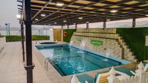 a swimming pool with a fountain in a building at استراحة الأسطورة AlAstura rest in Al Ḩamrāʼ