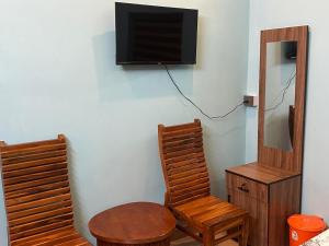 a room with two wooden chairs and a tv on a wall at SBJ Road House in Varkala
