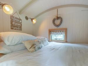 a bedroom with a white bed and a heart sign on the wall at Herbie's Shepherd Hut - Uk50229 in Nottingham