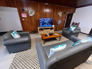 a living room with two couches and a flat screen tv at Muaitale House in Suva