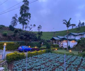 a house with a blue car parked in front of a garden at Whispering Hills in Nuwara Eliya