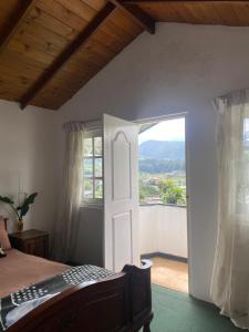 a bedroom with a bed and an open door at Whispering Hills in Nuwara Eliya +3 photos