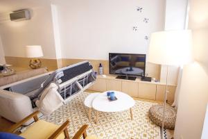 ein Wohnzimmer mit einem Sofa und einem TV in der Unterkunft Carmo in Chiado Apartment in Lissabon