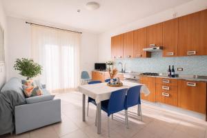 a kitchen and living room with a table and blue chairs at Residence I Delfini in Cupra Marittima