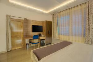a bedroom with a bed and a desk and a television at Sharnam On The Ganges in Rishīkesh +24 photos