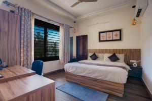 a bedroom with a bed and a desk and a window at Sharnam On The Ganges in Rishīkesh