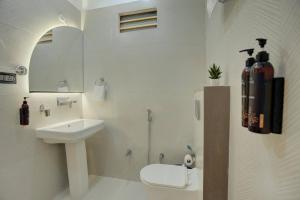 a white bathroom with a sink and a toilet at Sharnam On The Ganges in Rishīkesh