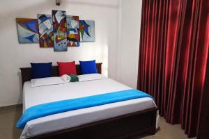 a bedroom with a bed with blue and red pillows at Vibes Home Stay in Athurugiriya
