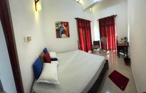 a bedroom with a white bed and red curtains at Vibes Home Stay in Athurugiriya