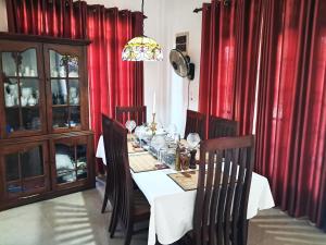a dining room with a table and red curtains at Vibes Home Stay in Athurugiriya