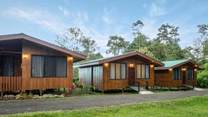 two wooden cottages with trees in the background at Termales del Arenal in Fortuna