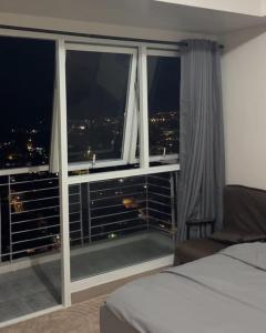 a bedroom with a large window with a city view at MERE Suite Davao- One Lakeshore behind SM Lanang in Davao City